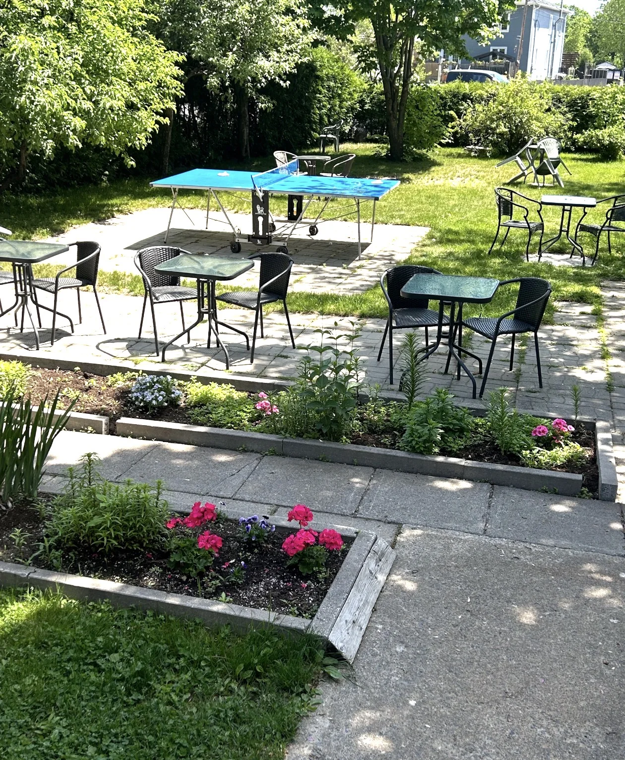 Jardin avec tables bistro et table de ping-pong au Motel des Patriotes