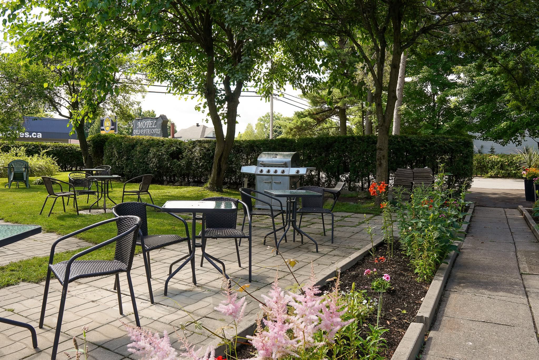 Espace extérieur ombragé avec tables et barbecue du Motel des Patriotes